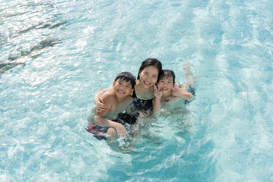 asian family, young boy son and 40s women mother having a good time playing and enjoying in swimming pool