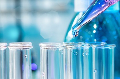 pipette with transparent drop over glass test tubes