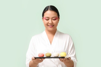 beautiful asian woman with tasty japanese mochi on color background