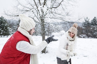 happy couple doing a snowball fight together in winter