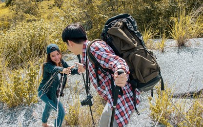 asian couple man and woman wearing casual clothes, smiling with happiness, helping, adventure traveling together and hiking mountains with backpacks in summer vacation trip