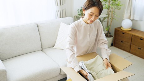 asian woman putting clothes away in a box