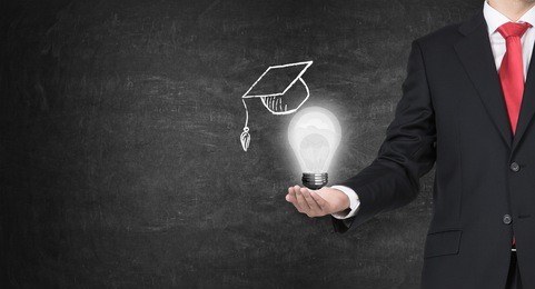a hand holding a mortarboard with a light bulb, concept of education. 