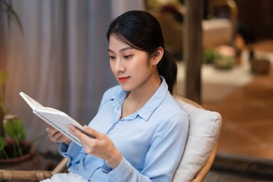 young asian woman reading book at home