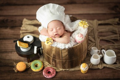 happy adorable cute asian newborn baby wearing chef hat sleeping with donuts prop
