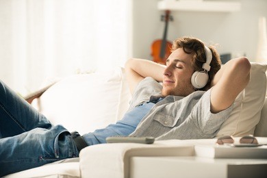 young man relaxing on sofa with headphones in the living room.