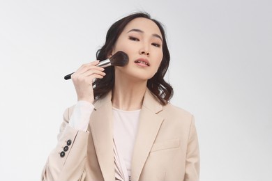 a horizontal photo, a pretty young asian girl holding brush for makeup. beauty of women. professional makeup and beauty, isolated on white background. beauty concept. 