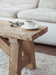 still life details, cup of coffee on rustic bench over white sofa