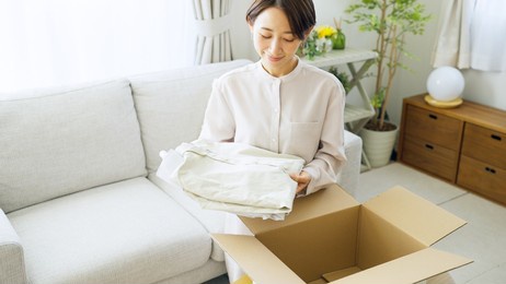 asian woman putting clothes away in a box