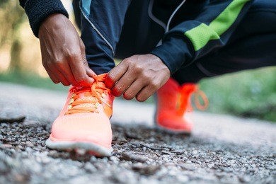 young woman tying laces of running shoes before training