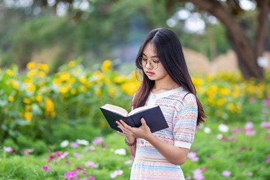 young beautiful asian woman reading book in the park, a woman read a book