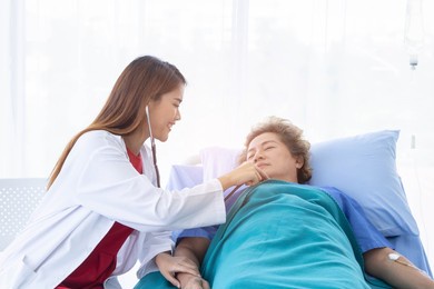 a young beautiful doctor is checking an old patient woman.