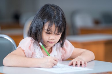 a female asian kid student concentrate writing on the examination paper in the class