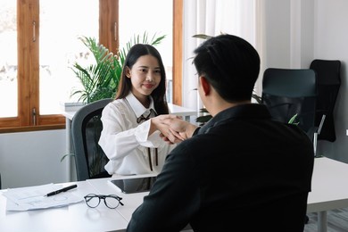 two business people handshake at meeting table in office together with confident. young asian businessman and businesswoman workers express agreement of investment deal