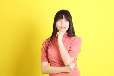 the teen asian girl with casual dressed standing on the yellow background.
