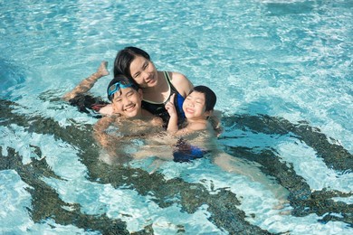 asian family, young boy son and 40s women mother having a good time playing and enjoying in swimming pool