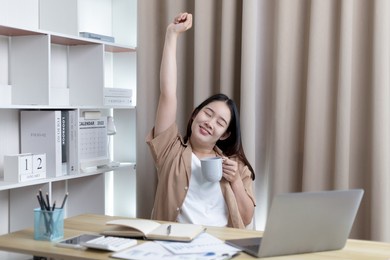 young asian female employee is doing a relaxing posture after a hard midday's work, happy women resting at work after work is finished, fatigue is eased, women working at home, relax.