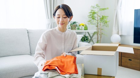 asian woman putting clothes away in a box
