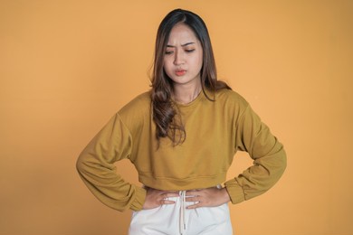 young asian woman in pain with both hands holding stomach
