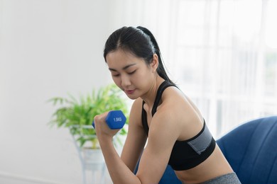 asian young woman workout exercise with dumbbells to build bicep curl muscle.arm day workout.athlete woman concentration exercise on arm to focus on bicep curl.workout and excercise with dumbbells.