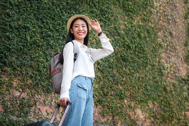 asian woman tourists is traveling on holiday trip with hat and holding luggage while preparing to get to the airport