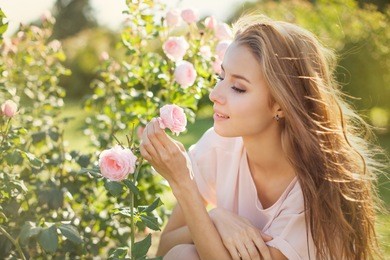 beautiful young woman smelling a rose flower