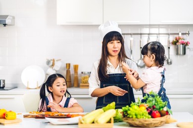 portrait of enjoy happy love asian family mother and little asian girl daughter child having fun help cooking food healthy eat together with fresh vegetable salad and sandwich ingredient in kitchen