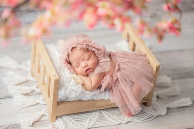 cute and adorable asian newborn baby girl sleeping on bed withpink flower in foreground