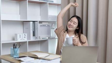 young asian female employee is doing a relaxing posture after a hard midday's work, happy women resting at work after work is finished, fatigue is eased, women working at home, relax.