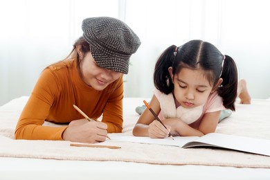 4k 50fps happy sibling girls helping cute kindergarten kids draw and play together in bed. use colored pencils to draw pictures on paper. happily concept family and learning