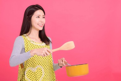 happy young woman housewife wearing kitchen apron while cooking