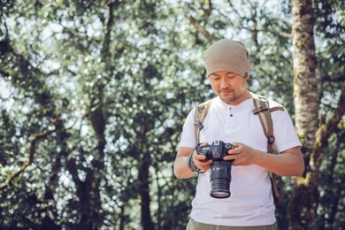 young male professional photographer holding camera outdoors at the park
