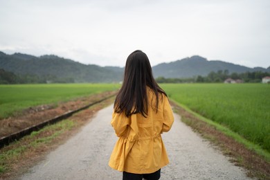 long hair asian lady looking at the vibrant green paddy field. girl walk at typical asian paddy field country side. 