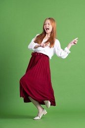 beautiful young asian woman dancing and posing on green background