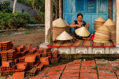 old vietnamese woman making a traditional conical hat at her home