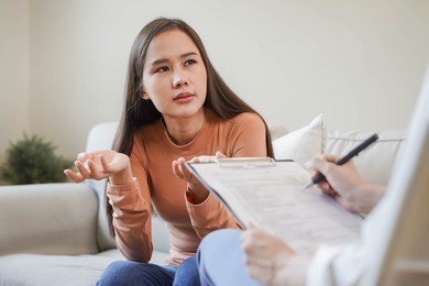 psychology, depression. sad, suffering asian young woman consulting with psychologist, psychiatrist while patient counseling mental with doctor woman taking notes at clinic. encouraging, therapy.