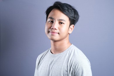 close up portrait of young smiling asian cute teen boy looking at camera posing at studio. grey isolated.