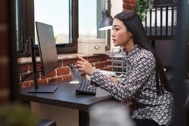 confident business office worker reasearching project marketing strategy while using work computer and sitting at desk. financial agency businesswoman reviewing business plan while in workspace.