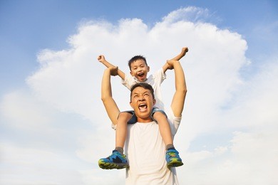 happy little boy  sitting on father's shoulder