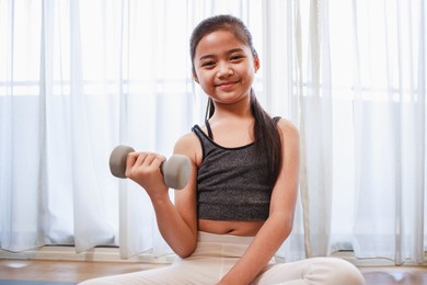 little girl doing exercise at home on a yoga mat in the living room at home. new normal concept. healthy lifestyle. relaxing at home