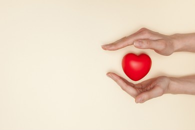 health, medicine and charity concept - close up of female hands with small red heart. flat lay.