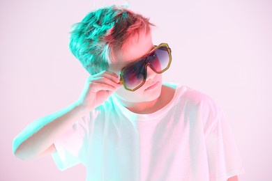 portrait of a stylish pre-teen boy in white t-shirt and fashionable sunglasses looking seriously away. studio portrait in mixed light. kid's fashion.