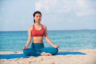 asian yoga girl doing flexibility yoga exercise on mat. peaceful girl sitting in forward bend exercise, head to knees uttanasana pose, outdoor woman doing gymnastic physical training exercise.