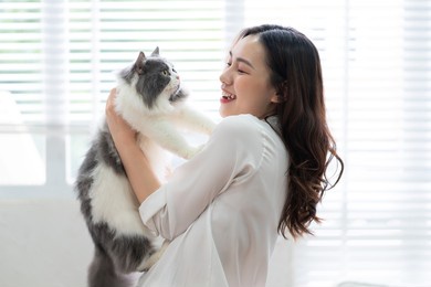 young asian woman playing with cat at home