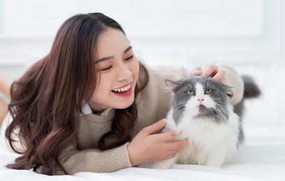 young asian woman playing with cat at home
