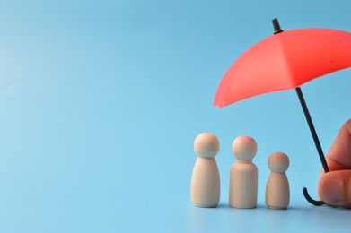 red toy umbrella and wooden doll figures isolated on a blue background. insurance coverage concept.