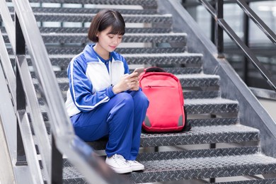 female students wearing school uniforms, using a mobile phone