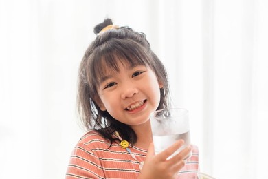water drink.kid girl smile and drinking water from glass isolate white banner background.world water day, mineral water, fresh drinking, thirsty summer, wellness, healthcare.young asian child thirst.