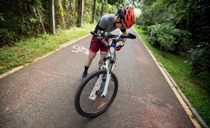 woman cyclist set the seat height of bike at park on sunny day