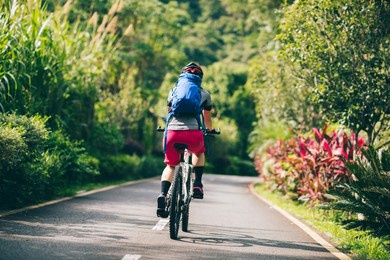 woman cycling on tropical park trail in summer